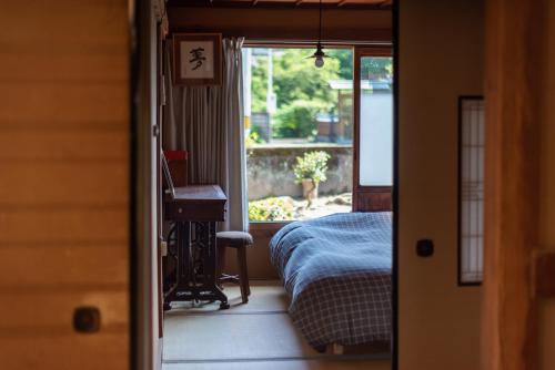 AkiHostel 東風ノ家（Kochi-no-ya）的一间卧室配有一张床、一张书桌和一个窗户。