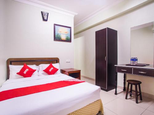 黑风洞Super OYO 89363 Casavilla Hotel的一间卧室配有一张带红色枕头的床和一张书桌