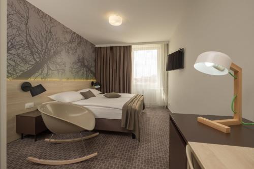 卢布尔雅那B&B Hotel Ljubljana Park的配有一张床和一把椅子的酒店客房