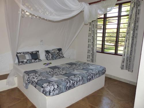 迪亚尼海滩Safina Cottages的一间卧室配有一张带天蓬的床