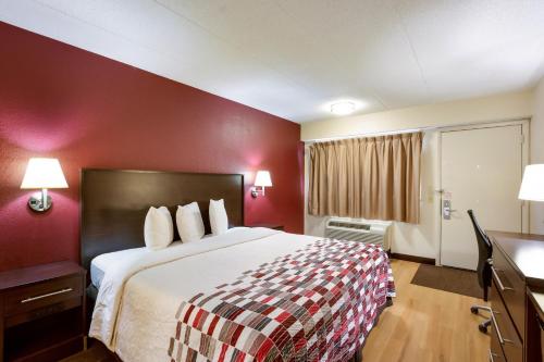 卡拉马祖Red Roof Inn Kalamazoo East – Expo Center的酒店客房,设有一张红色墙壁的大床