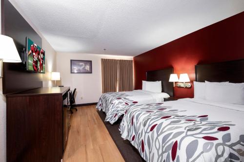 多佛尔Red Roof Inn & Suites Dover Downtown的红色墙壁的酒店客房内的两张床
