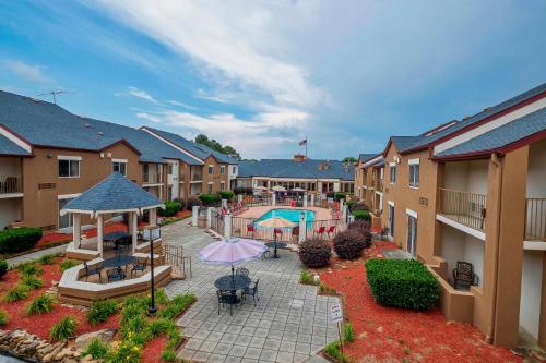 诺克斯维尔Red Roof Inn PLUS+ & Suites Knoxville West - Cedar Bluff的公寓大楼设有带游泳池和遮阳伞的庭院。