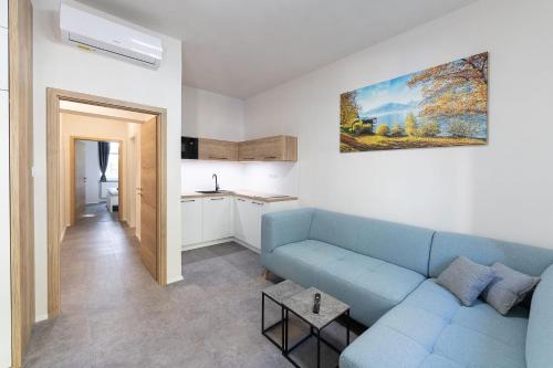 比尔森Apartsee Wellness Plzeň的一间带蓝色沙发的客厅和一间厨房