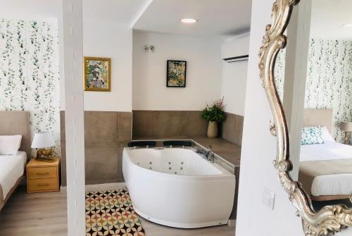 蒙帕亚Hotel Finca Alcamino的带浴缸、床和镜子的浴室