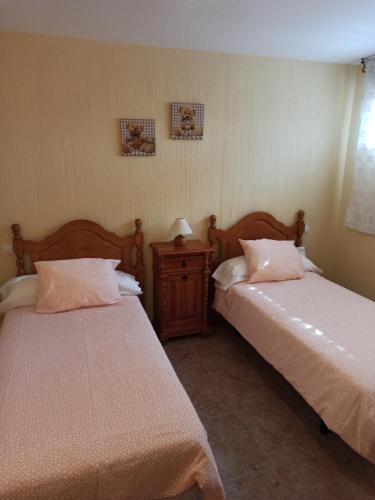 Robledillo de la JaraAlojamiento rural "LA JARA"的一间卧室配有两张床和一张带台灯的桌子
