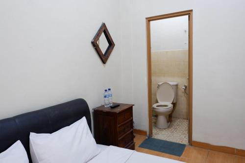 日惹Khresna Guest House Malioboro Mitra RedDoorz的一间卧室配有一张床、一个卫生间和一面镜子