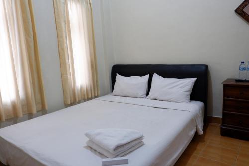 日惹Khresna Guest House Malioboro Mitra RedDoorz的一间卧室配有带白色床单和枕头的床。