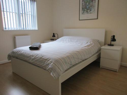 拉格比20 Nightingale Gardens, Coton Park, Rugby CV23 0WT的卧室内的一张白色床,设有2个床头柜