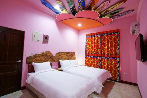 台东马卡巴嗨文创民宿的配有粉红色墙壁的客房内的两张床