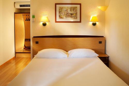 阿朗松钟楼阿伦松酒店的卧室配有一张带两个枕头的大白色床