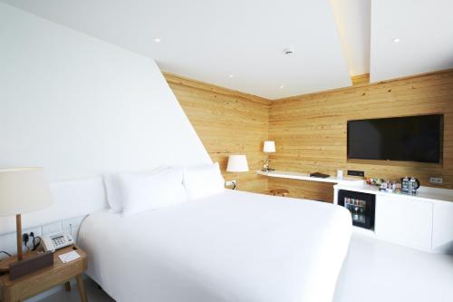 梅尔皮姆罗勇盛泰乐萨帕雅度假村的卧室配有白色的床和平面电视。