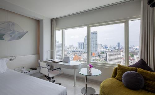 曼谷Centara Watergate Pavilion Hotel Bangkok的配有一张床、一张书桌和一扇窗户的酒店客房