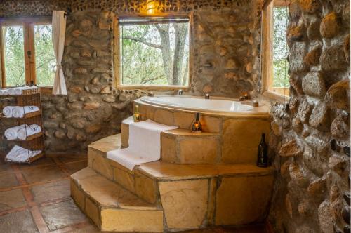 奈瓦沙Honeymoon Hut的带浴缸和窗户的石质浴室