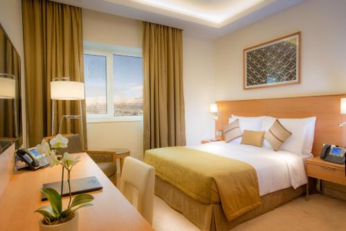 苏莱曼尼亚Millennium Kurdistan Hotel & Spa的配有一张床和一张书桌的酒店客房