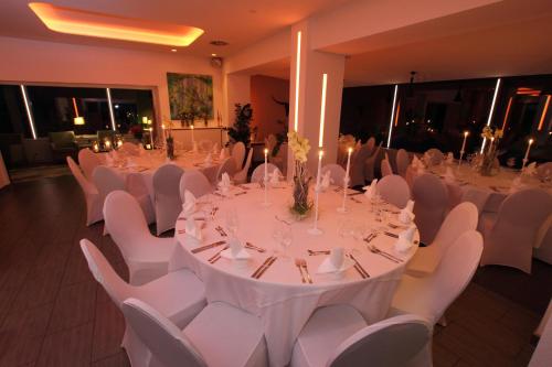 帕滕森zeitlos Hotel und Restaurant am Fuchsbach的宴会厅配有白色的桌子和白色的椅子