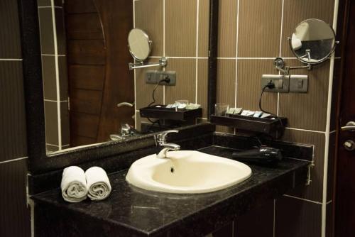 达累斯萨拉姆蓝宝石酒店的浴室配有盥洗盆、镜子和毛巾