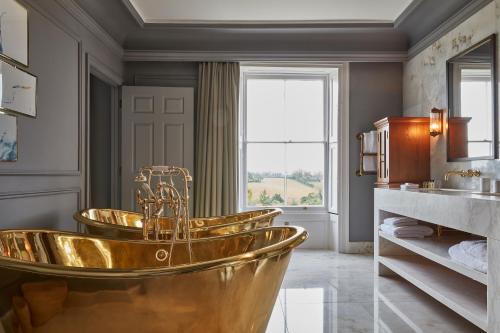 埃克斯茅斯林浦斯通庄园酒店的带窗户的浴室内的金色浴缸