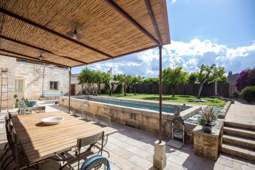 GiuggianelloAntica Dimora Giardini Segreti的一个带木桌和椅子的庭院和一个游泳池