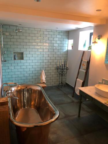 曼彻斯特Chorlton Garden Rooms. Relax, work, stay and play.的一间带铜浴缸和水槽的浴室