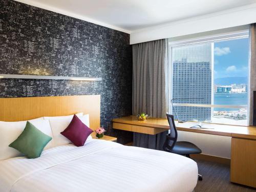 香港香港诺富特世纪酒店的配有一张床、一张书桌和一扇窗户的酒店客房