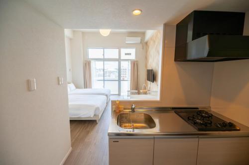 那霸Hotel Tomas Asahibashi Station的一个带水槽的厨房和一张位于客房内的床