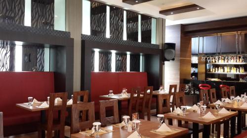 Banjarbaru罗迪萨班亚尔巴鲁酒店的一间带木桌椅的餐厅和一间酒吧