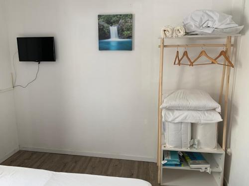 锡拉奥Hôtel le petit randonneur的客房设有一张床和一个带电视的架子