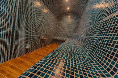 巴尼亚Seven Springs Hotel的浴室的墙壁上铺有蓝色瓷砖,设有淋浴。