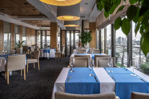 基辅CITYHOTEL的餐厅设有蓝色的桌椅和窗户。