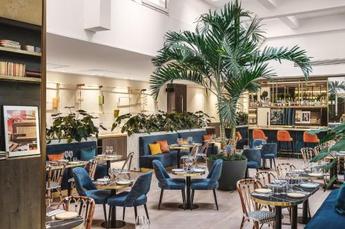 巴黎PLEY Hotel的一间设有桌椅的餐厅,并种植了棕榈树