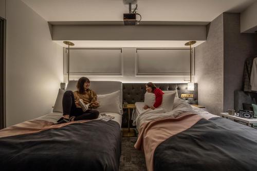 川崎slash kawasaki的两名妇女坐在酒店房间的床边