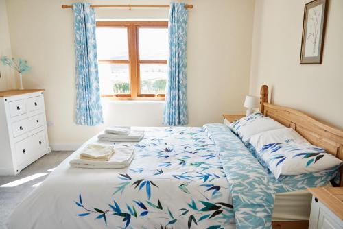 EdlinghamFinest Retreats - Quail's Nest Cottage的一间卧室配有一张带蓝色窗帘的床和一扇窗户