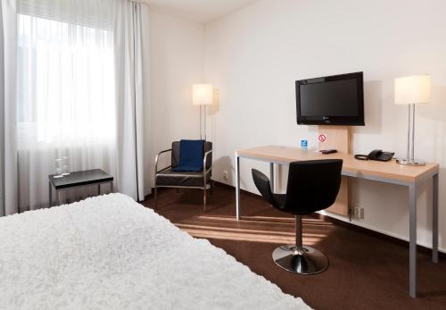 夏洛滕贝格Hotell Charlottenberg的一间卧室配有一张床、一张书桌和一台电视。