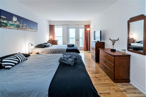 魁北克市Le Théâtral - En plein coeur de l'action avec stationnement的一间卧室配有两张床、一个梳妆台和镜子