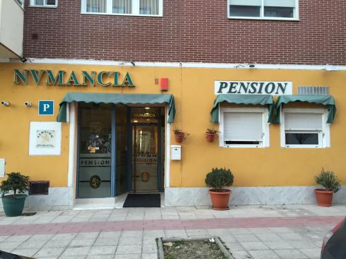 布尔戈斯Alojamiento Numancia Pensión的黄色建筑,有餐厅入口