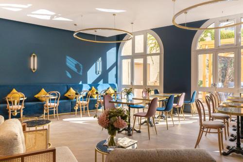 巴黎voco Paris Montparnasse, an IHG Hotel的餐厅拥有蓝色的墙壁和桌椅