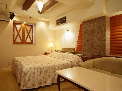 岬町Hotel Fine Misaki的一间卧室配有一张床、一张沙发和一张桌子