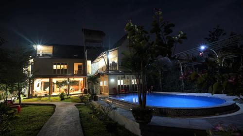 芹苴Mekong Delta Ricefield Lodge的夜间在房子前面的游泳池