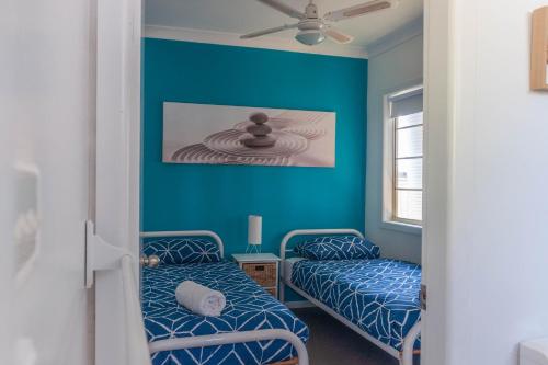 MyolaThe Jetty House Jervis Bay的蓝色墙壁客房的两张床