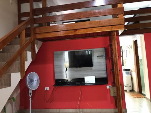 蒙加瓜Apartamento no Centro de Mongaguá的一张高架床,在红色的墙上配有平面电视