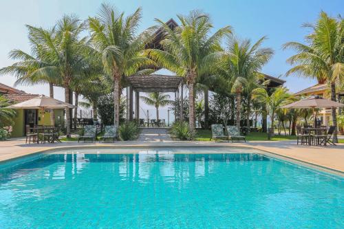 巴拉奈里奥-坎布里乌Praia do Estaleiro Guest House的一座棕榈树和椅子的大型游泳池