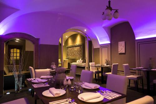 布拉格U十字酒店的餐厅配有桌椅,灯光紫色