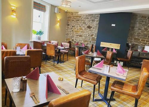 特里迪格Tredegar Arms Hotel的餐厅配有桌椅和粉色纸