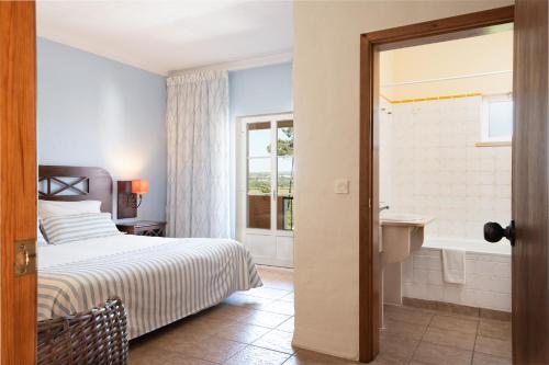圣安德烈莱茨利亚山乡村酒店的一间卧室配有一张床,浴室设有浴缸