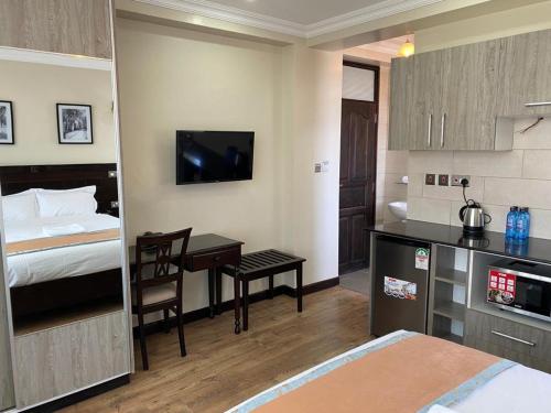内罗毕Hemak Suites的酒店客房带一张床铺、一张书桌和一间卧室