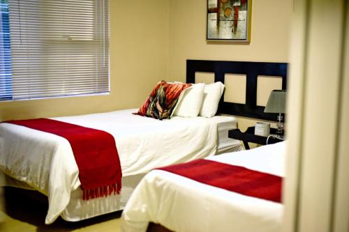 埃祖尔韦尼Valleyside Executive Apartments的一间卧室配有两张带红色毯子的床。