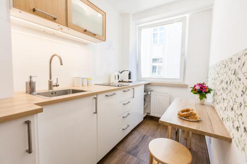 克拉科夫Vintage Tomasza 25 Apartments的厨房配有白色橱柜和木桌