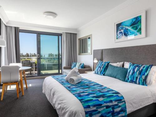 凯阿玛Sebel Harbourside 301 Kiama的酒店客房设有一张大床和一张桌子。