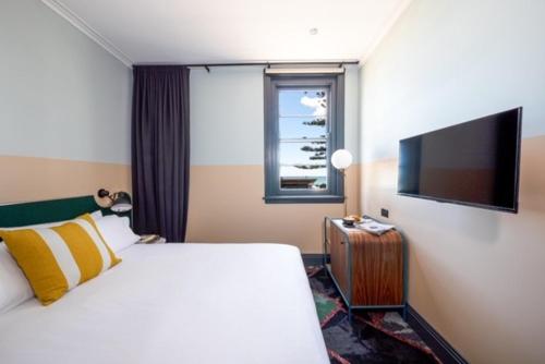悉尼Stay at Hotel Steyne的配有一张床和一台平面电视的酒店客房